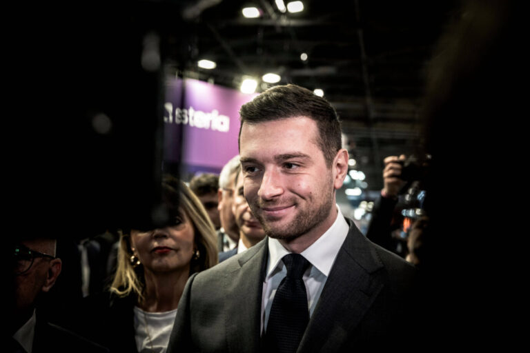 Mit schwarzem Jackett und schwarzer Krawatte grinst er in die Kamera: Der Vorsitzende des Rassemblement Nationa, Jordan Bardella