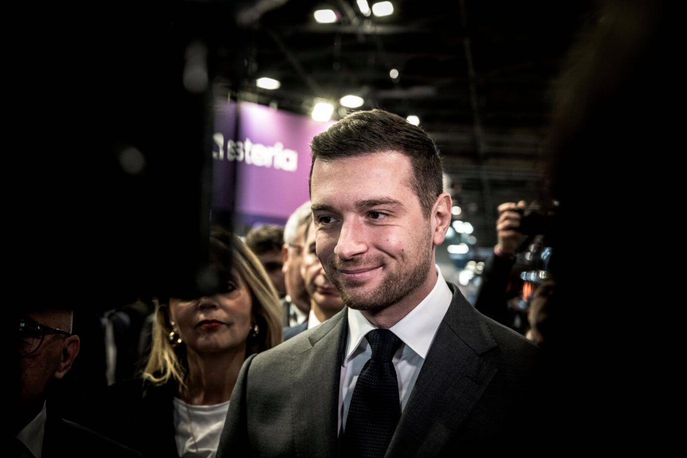 Mit schwarzem Jackett und schwarzer Krawatte grinst er in die Kamera: Der Vorsitzende des Rassemblement Nationa, Jordan Bardella