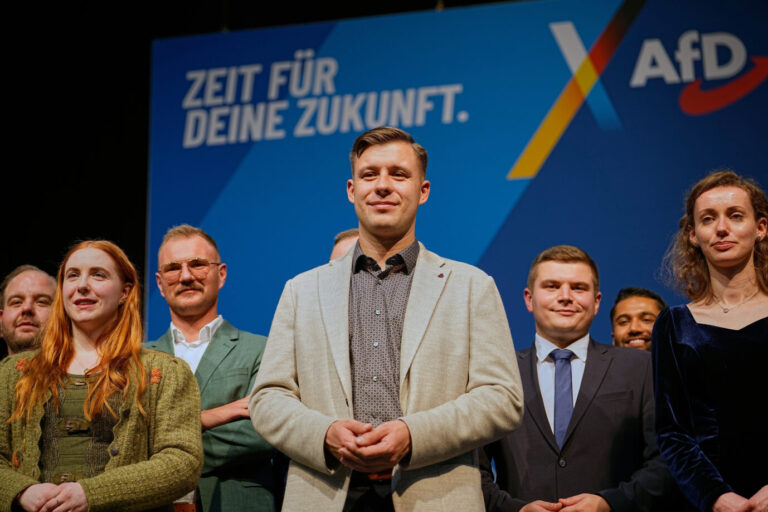 Vor einer blauen Wand mit Logo der Mutterpartei AfD stehen mehrere junge Menschen, es handelt sich um den frisch gewählten Vorstand der Generation Deutschland, Jean-Pascal Hohm in der Mitte, viele der Gewählten zählen zum Helferich-Lager