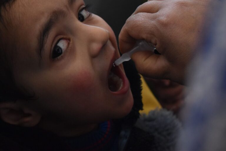 Das Bild zeigt einen kleinen Jungen in Indien, der eine Schluckimpfung gegen Kinderlähmung bekommt.
