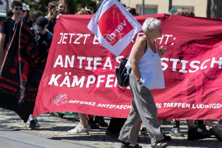 Das Bild zeigt eine alte Frau mit einer Verdi-Fahne vor einer Antifa-Demonstration. Das Grundgesetz sieht nicht vor, daß Gewerkschaften gegen Parteien agitieren.