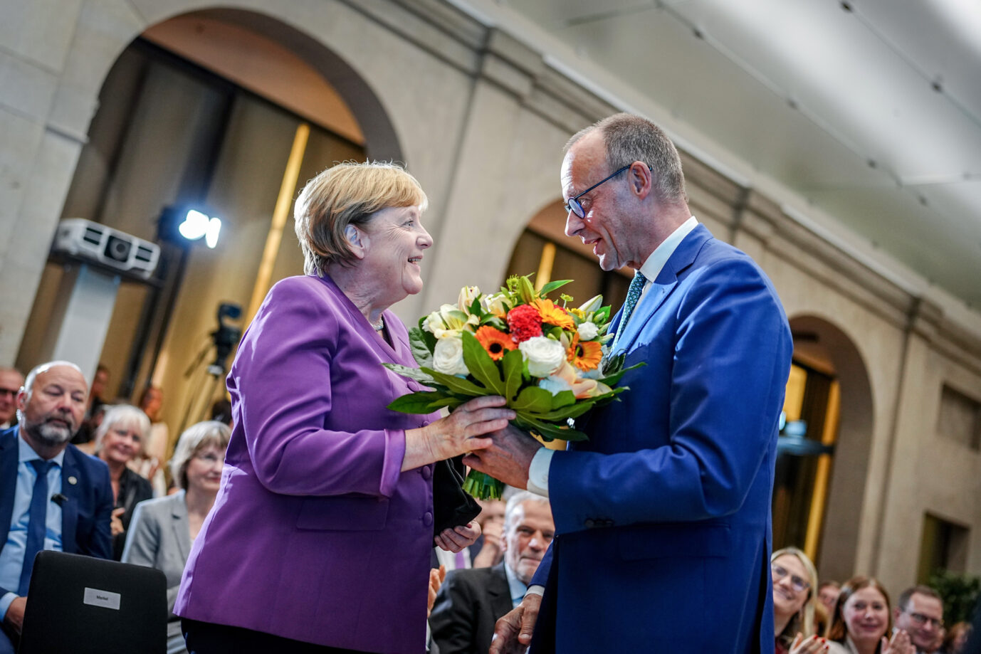 Friedrich Merz, CDU-Bundesvorsitzender und Unionsfraktionsvorsitzender, überreicht Angela Merkel beim Berliner Gespräch Spezial zum 70. Geburtstag der früheren Bundeskanzlerin einen Blumenstrauß.