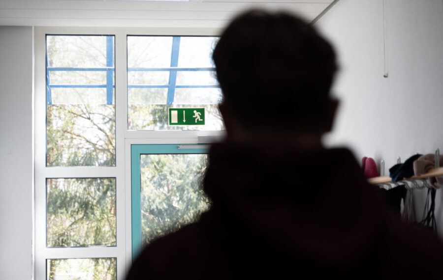 Ein Schüler steht im Flur einer Schule und blickt auf ein Ausgangsschild. Schüler blickt auf den Ausgang: In Berlin wurde ein 18jähriger für Kritik an einem woken Workshop rausgeworfen. Foto: picture alliance/dpa | Leonie Asendorpf