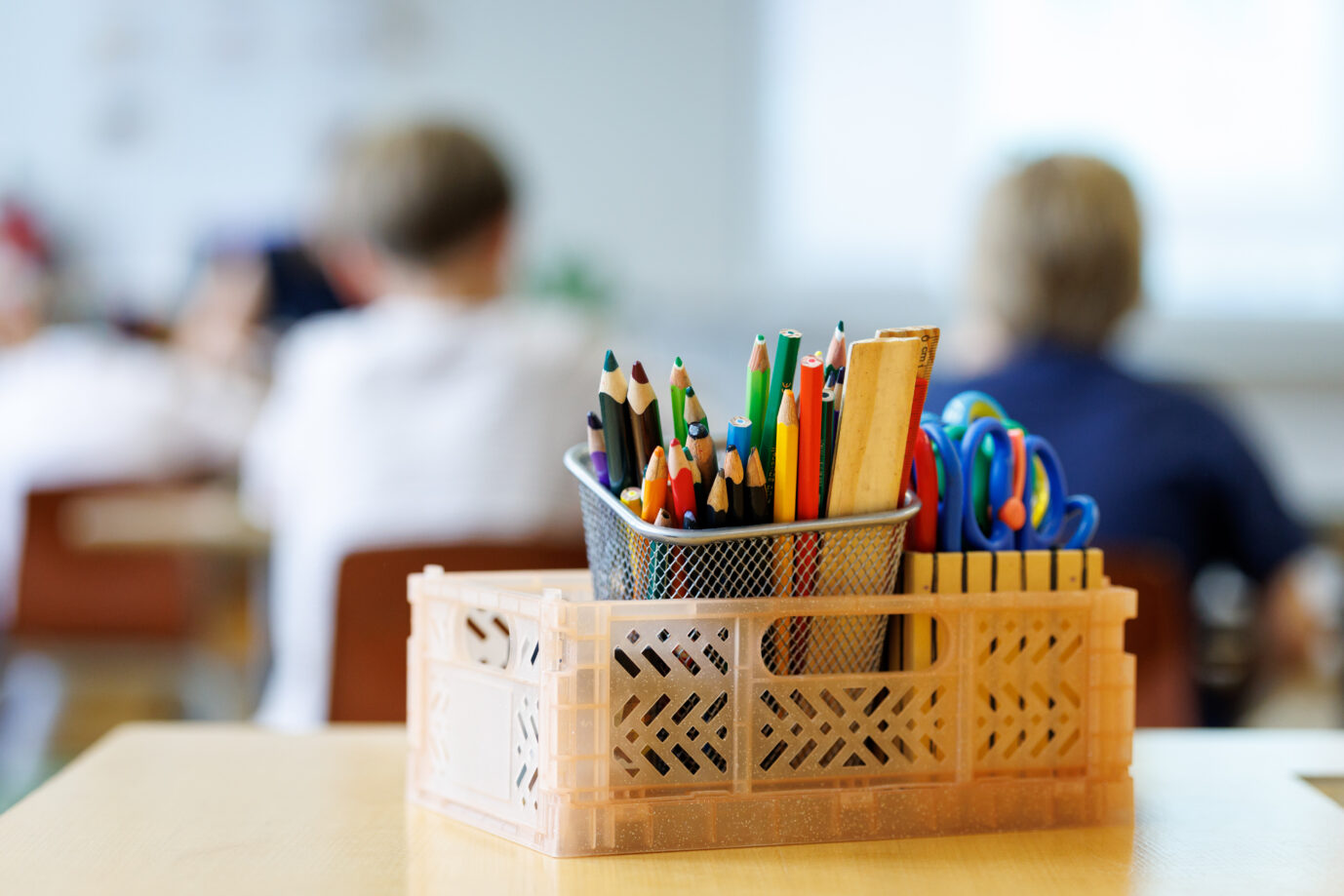 Schüler einer zweiten Klasse einer Grundschule in München (Bayern) sitzen während des Unterrichts auf ihren Plätzen und arbeiten an einer Schulaufgabe, während im Vordergrund ein Kasten mit Stiften, Linealen und Scheren zu sehen ist. Dividieren soll einfacher werden.