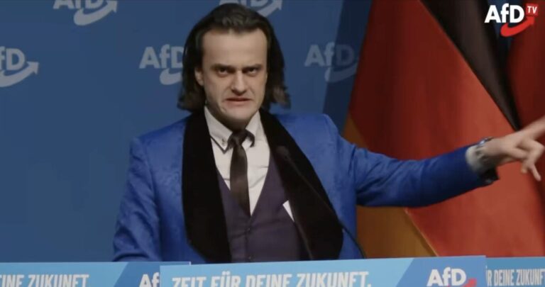 Ein Mann mit schulterlangen schwarzen Haaren zieht eine Fratze und gestikuliert mit den Händen: Alexander Eichwald, der bald aus der Partei fliegt