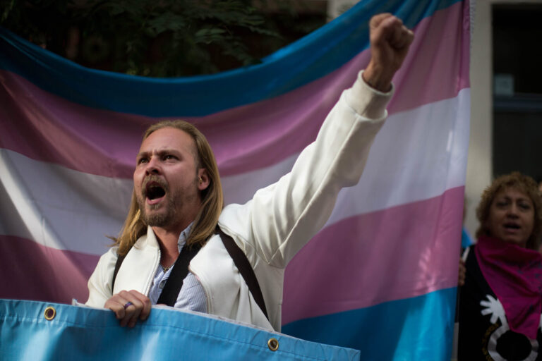 Ein Aktivist vor einer Transflagge