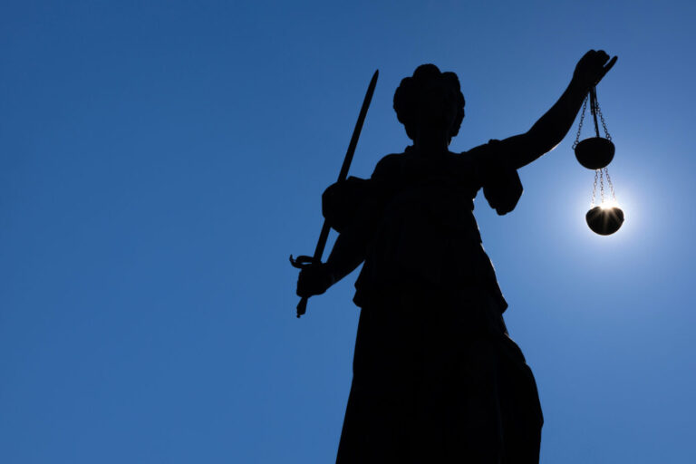 Die Silhouette der Justitia-Statue auf dem Römerberg in Frankfurt am Main zeichnet sich gegen Sonne ab. Dabei hat es den Anschein, als läge die Sonne in Ihrer Gerechtigkeitswaage. Justitia soll blind urteilen: Die taz setzt im Fall eines Richters auf Indizien statt Beweise. Foto: picture alliance / greatif | Florian Gaul
