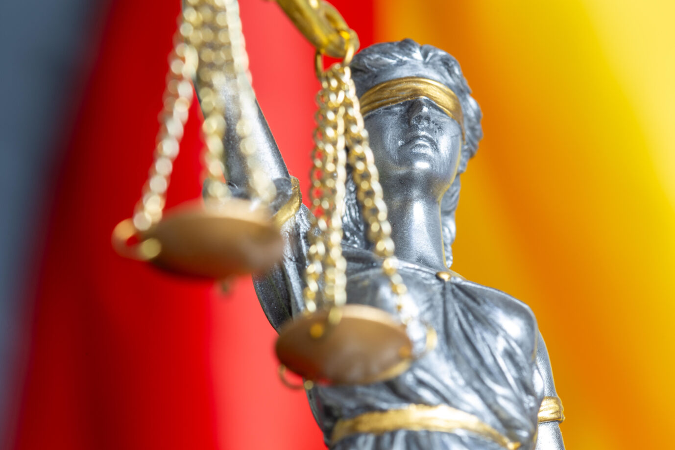 Nahaufnahme einer Justitia vor der Flagge von Deutschland (Symbolbild). Behörde verliert gegen die JUNGE FREIHEIT