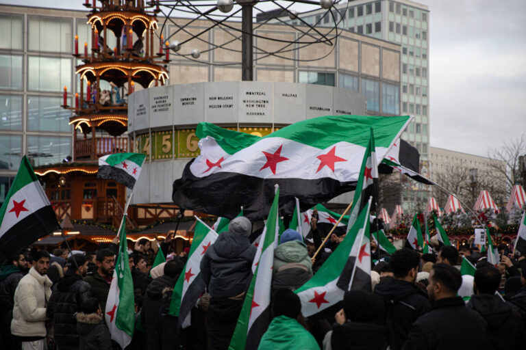 Syrer ziehen mit ihren Landesfahnen im Dezember über den Weihnachtsmarkt am Berliner Alexanderplatz.