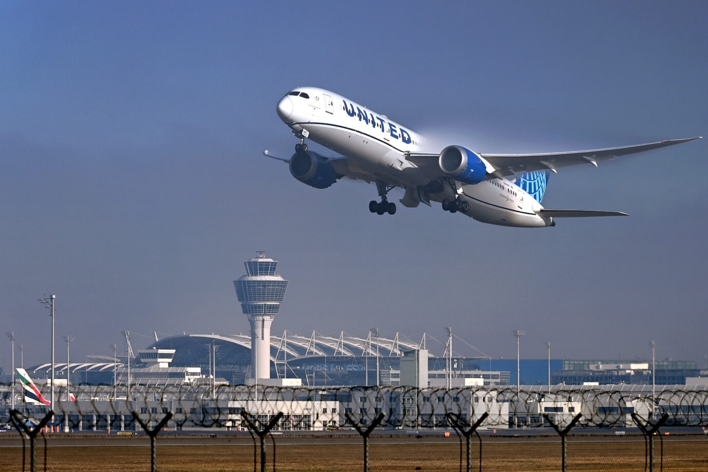 Ein Flugzeug hebt vom Münchener Flughafen ab in einen blauen Himmel– ein Symbolbild für Abschiebungen und Migration