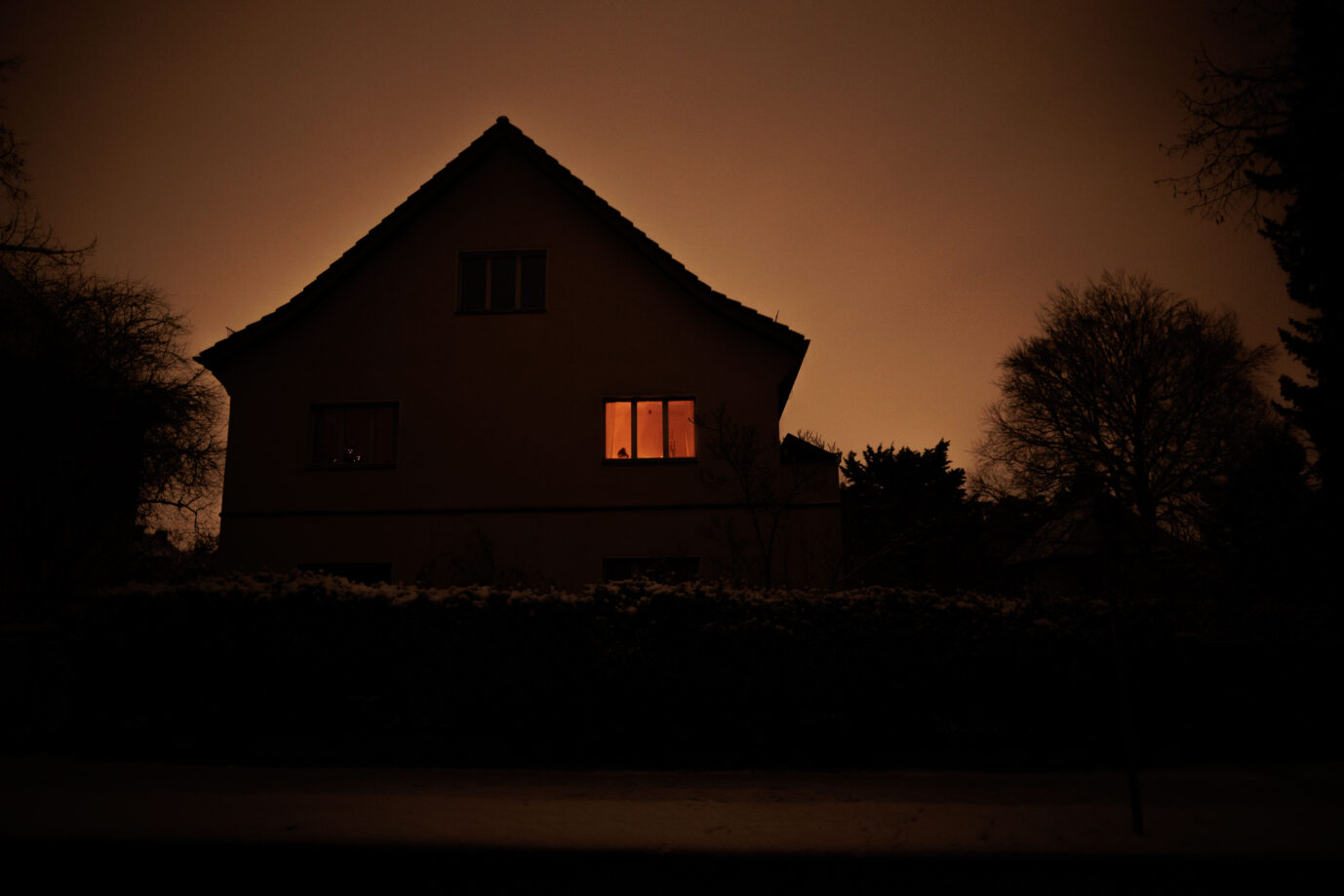 Ein vom Stromausfall betroffenes Haus in Berlin. Hinter einem Fenster schimmert Kerzenlicht hervor.