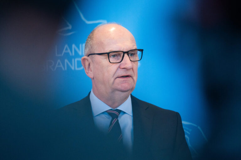 Porträtaufnahme von Dietmar Woidke in dunklem Anzug und Krawatte, stehend vor blauem Hintergrund mit Landesemblem, aufgenommen während eines Statements in der Potsdamer Staatskanzlei. Woidke äußerte sich dort zur Koalitionskrise in Brandenburg und begründete den Bruch der bundesweit einzigen SPD-BSW-Landesregierung mit einer fehlenden Vertrauensbasis. Dietmar Woidke in der Staatskanzlei: Der Ministerpräsident erklärte das Ende der SPD-BSW-Koalition. Foto: picture alliance/dpa | Christophe Gateau