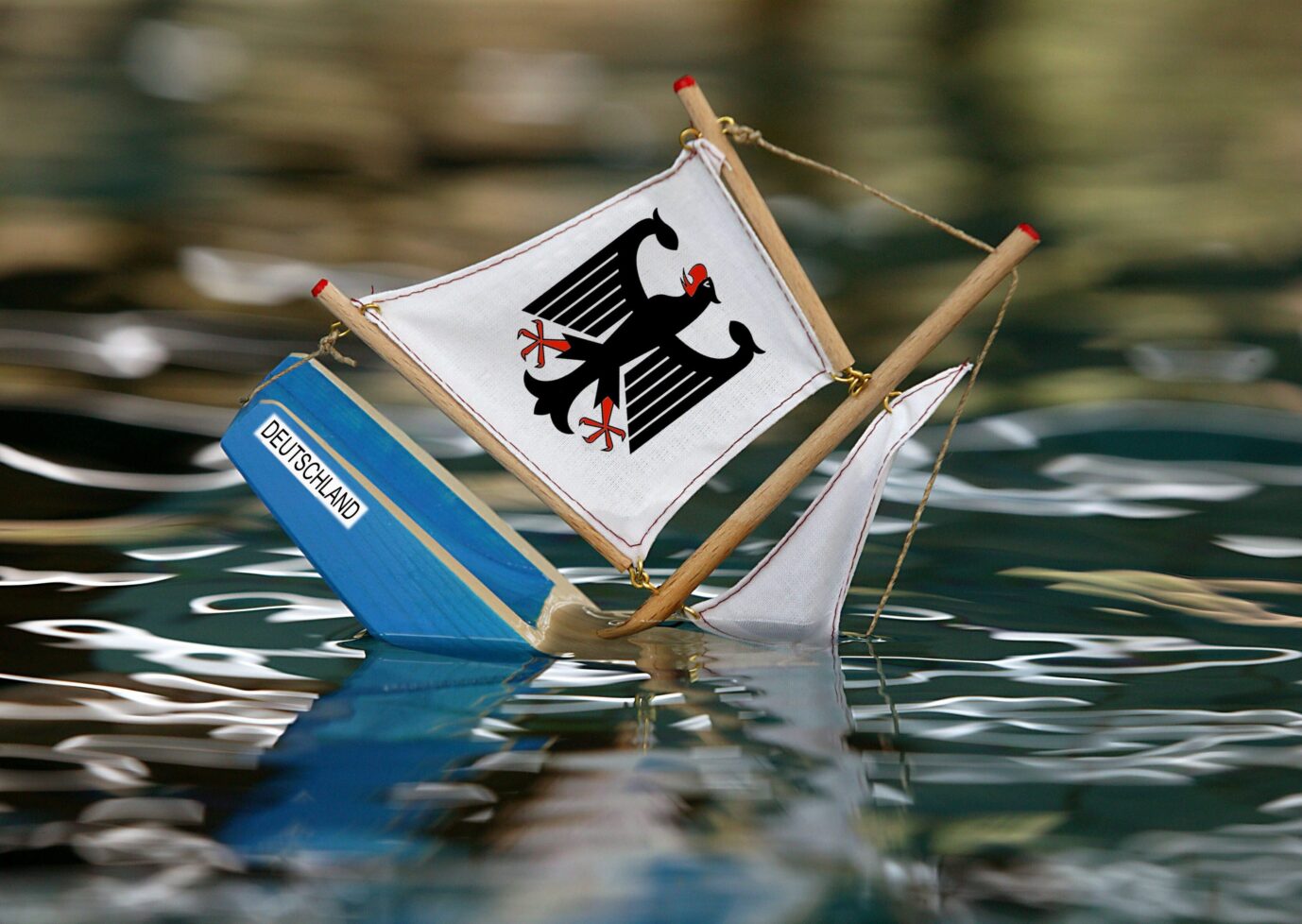 Ein kleines Schiff mit einem Bundesadler auf dem Segel sinkt – Symbolbild für Deutschlands Krise