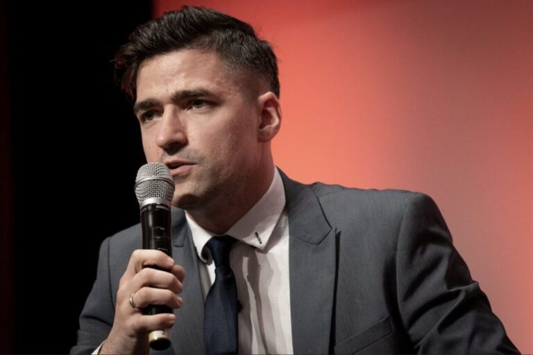 Der Chef der Identitären Bewegung Österreich, Martin Sellner, trägt einen grauen Anzug und spricht in ein Mikrofon