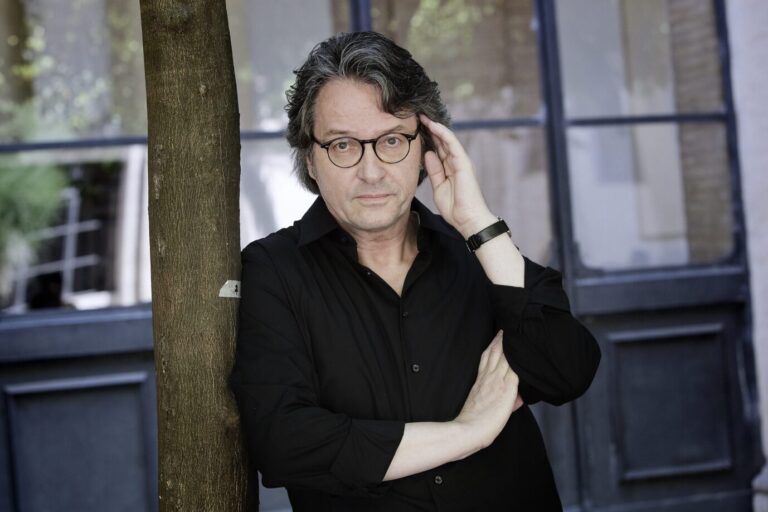 Der Schriftsteller Ralf Rothmann lehnt sich an einen Baum an und hält nachdenklich den Kopf in den Händen.