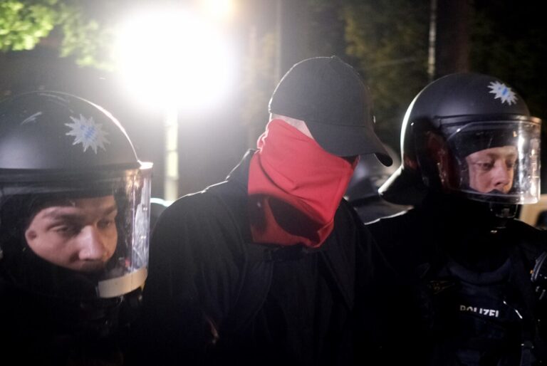 Polizisten führen einen vermummten Mann bei einem nächtlichen Einsatz ab. Szene aus Leipzig-Connewitz nach Ausschreitungen bei Demonstrationen der linken Szene im Umfeld des Lina-Prozesses, bei denen es zu Zusammenstößen zwischen Vermummten und der Polizei kam. Polizeieinsatz in Leipzig: Der Fall der verurteilten Linksextremisten lenkt den Blick auf staatlich finanzierte Arbeitgeber und deren Umgang mit politischer Gewalt. Foto: picture alliance/dpa | Sebastian Willnow