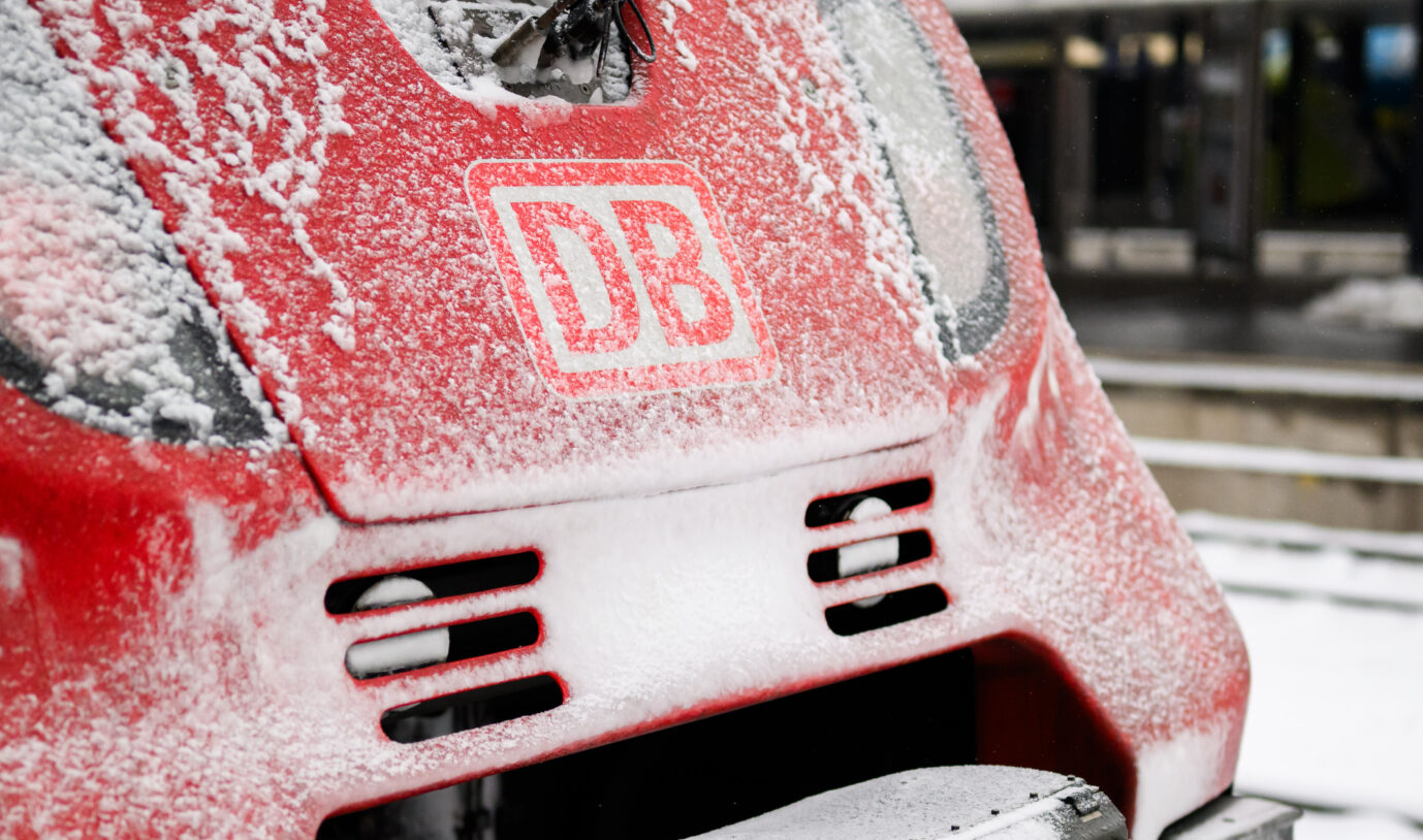 Front eines roten Triebwagens der Deutschen Bahn mit verschneitem DB-Logo an einem Bahnsteig – Kontext zum tödlichen Angriff auf einen Schaffner bei einer Ticketkontrolle im Kreis Kaiserslautern. Ein Regionalzug der Deutschen Bahn: Ein Zugbegleiter ist nach einem Prügelangriff durch einen Schwarzfahrer gestorben. Foto: picture alliance/dpa | Julian Stratenschulte