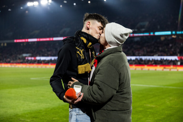 Zwei Männer küssen sich am Spielfeldrand eines Fußballstadions, einer hält eine geöffnete Ringschatulle in der Hand. Der bisexuelle Amateur-Schiedsrichter Pascal Kaiser macht seinem Partner vor dem Bundesligaspiel des 1. FC Köln einen Heiratsantrag; das Bild verbreitet sich bundesweit, während gegen ihn strafrechtliche Vorwürfe im Raum stehen. Pascal Kaiser im Rheinenergie-Stadion: Kuß nach dem Heiratsantrag vor dem Bundesligaspiel des 1. FC Köln. Foto: picture alliance / BEAUTIFUL SPORTS | Steffie Wunderl