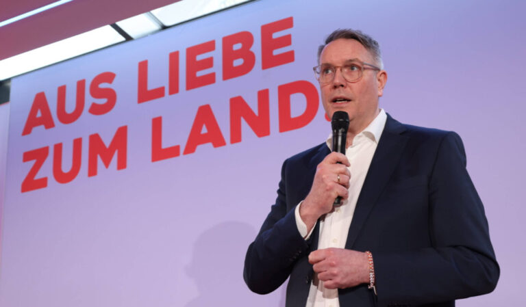 Alexander Schweitzer steht mit Mikrofon vor einem Banner mit der Aufschrift „Aus Liebe zum Land“. Rheinland-Pfalz zahlte 2024 und 2025 laut Staatskanzlei mehr als 90.000 Euro an Journalisten. Alexander Schweitzer (SPD) bei einer Veranstaltung: Unter seiner Landesregierung flossen fünfstellige Summen an Journalisten. Foto: IMAGO / Frank Ossenbrink
