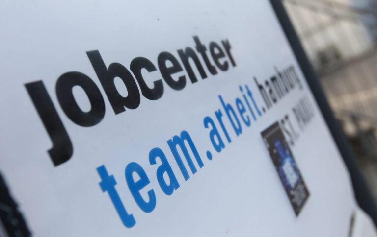 Aufnahme eines Schilderausschnitts des Jobcenters Team.arbeit.hamburg, auf dem der Schriftzug „jobcenter“ und „team.arbeit.hamburg“ zu sehen ist. Das Bild bezieht sich auf die Einladung des Jobcenters Hamburg zu einem gemeinsamen Fastenbrechen im Ramadan. Das Jobcenter gibt sich besonders vielfältig und bunt: Mit einem Rundschrieben werden Mitarbeiter zum islamischen Fastenbrechen geladen. Foto: IMAGO / Hanno Bode