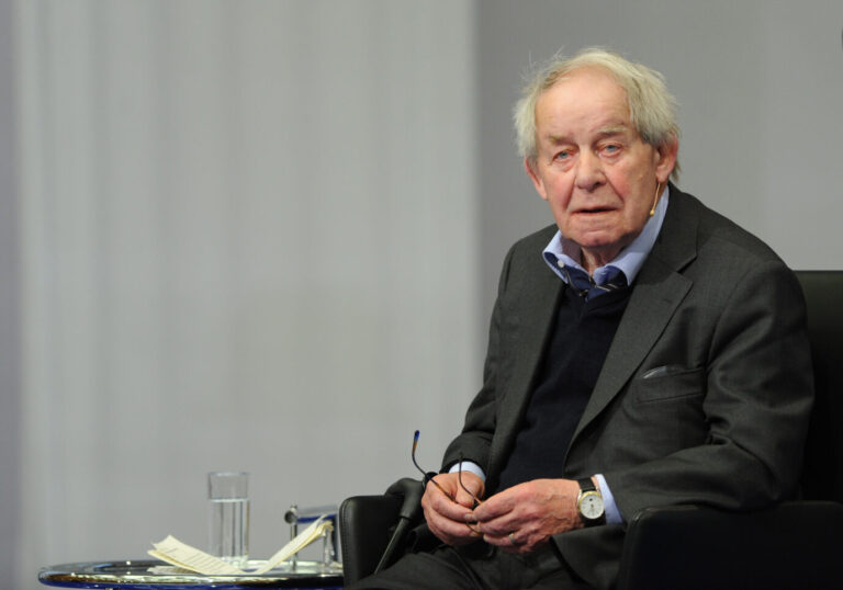 Der Schriftsteller Siegfried Lenz trägt ein graues Sakko und hält seine Brille in den Händen