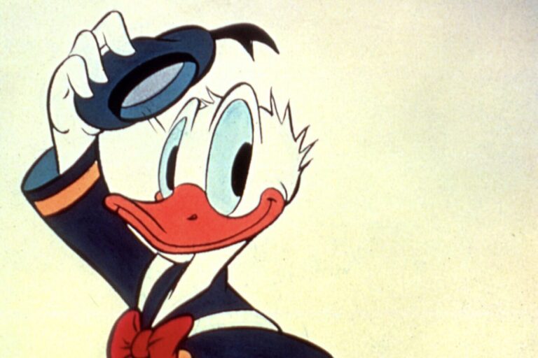 Zeichentrickfigur Donald Duck hebt lächelnd seinen Matrosenhut vor hellem Hintergrund, ikonische Figur aus den Disney-Comics von Carl Barks, der die Duck-Familie entscheidend prägte.