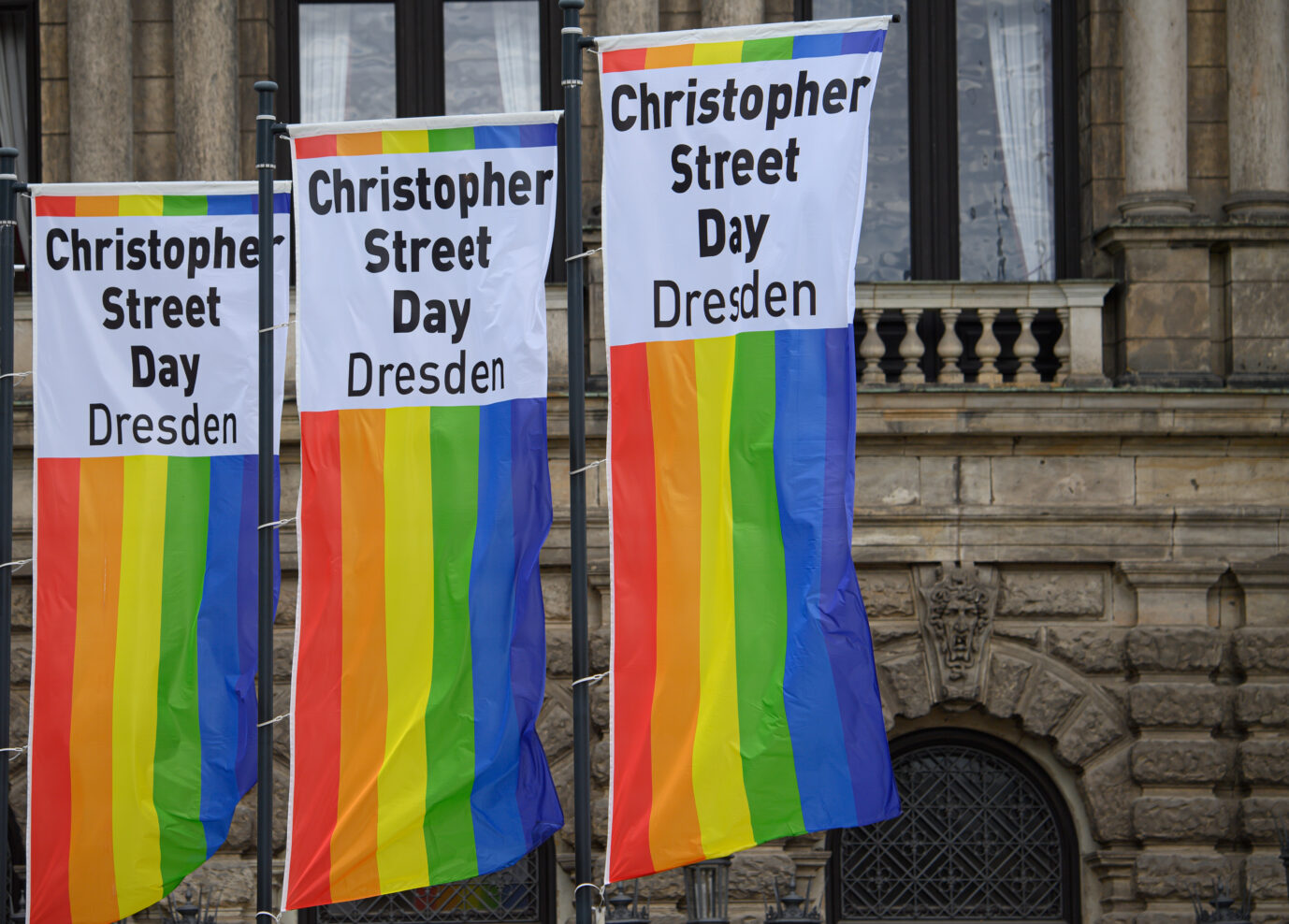 Regenbogenfahnen mit der Aufschrift Christopher Street Day Dresden wehen auf dem Theaterplatz vor der Semperoper an Fahnenstangen im Wind. Unter Beachtung der aktuellen Vorschriften zur Coronaprävention findet am 5. September 2020 der CSD mit einer Demonstration und einem Straßenfest in Dresden statt.