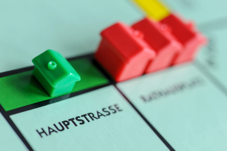 Nahaufnahme eines Monopoly-Spielfelds mit grünen und roten Häusern auf dem Feld „Hauptstraße“, sinnbildlich für Immobilienbesitz und dessen wachsende Kostenbelastung in Deutschland.Häusle auf der „Hauptstraße“: Neue Steuerpläne könnten Wohneigentum weiter belasten. Foto: picture alliance / FotoMedienService | Ulrich Zillmann