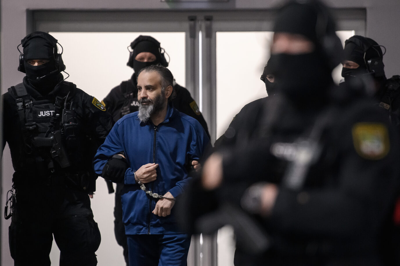 Justitzbeamte führen Taleb al-Abdulmohsen in den Gerichtssaal des temporären Gerichtsgebäudes vom Landgericht Magdeburg. Dort wurde am Morgen der Prozess gegen den Todesfahrer vom Magdeburger Weihnachtsmarkt fortgesetzt. Die Generalstaatsanwaltschaft wirft dem Mann aus Saudi-Arabien versuchten Mord in 338 Fällen vor. Kopf war offen.