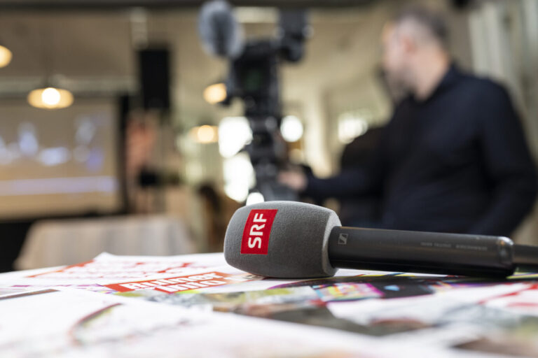 SRF-Mikrofon liegt auf einem Tisch vor einer Kamera bei einem Medientermin. Öffentlich-rechtlicher Rundfunk in der Schweiz: Eine Volksinitiative zur Senkung des Rundfunkbeitrages scheitert laut Hochrechnung deutlich. SRF-Mikrofon bei einem Medientermin: Die Schweizer weisen eine Senkung der Rundfunkabgabe in einer Volksabstimmung klar zurück. Foto: picture alliance/KEYSTONE | ALESSANDRO DELLA VALLE