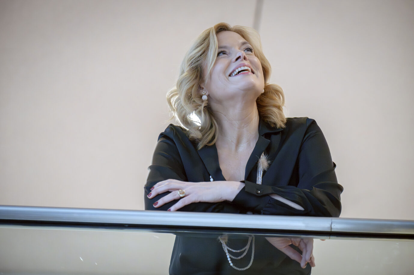 Blonde Frau mit schulterlangem Haar lehnt an einem Geländer, blickt nach oben und lächelt; sie trägt eine dunkle Bluse, Ohrringe und einen Ring, die Arme sind locker übereinandergelegt. Bundestagspräsidentin Julia Klöckner (CDU) im Reichstagsgebäude: Haare gut, alles gut. Foto: picture alliance / Geisler-Fotopress | Bernd Elmenthaler/Geisler-Fotopr