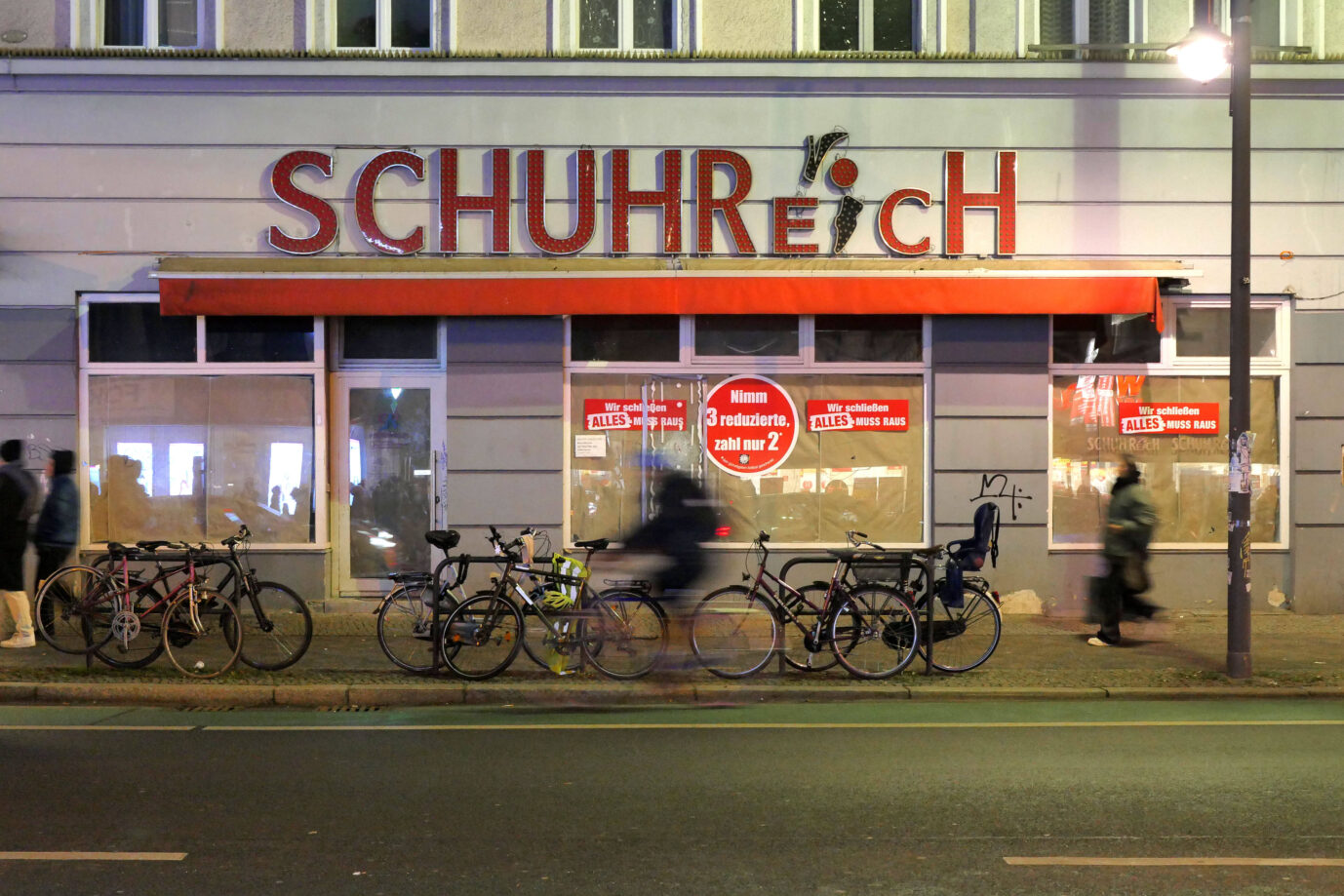 Ein Fahrradfahrer fährt an einem geschlossenen Schuhgeschäft in Berlin vorbei, der Laden macht nämlich dicht, weil er pleite ist