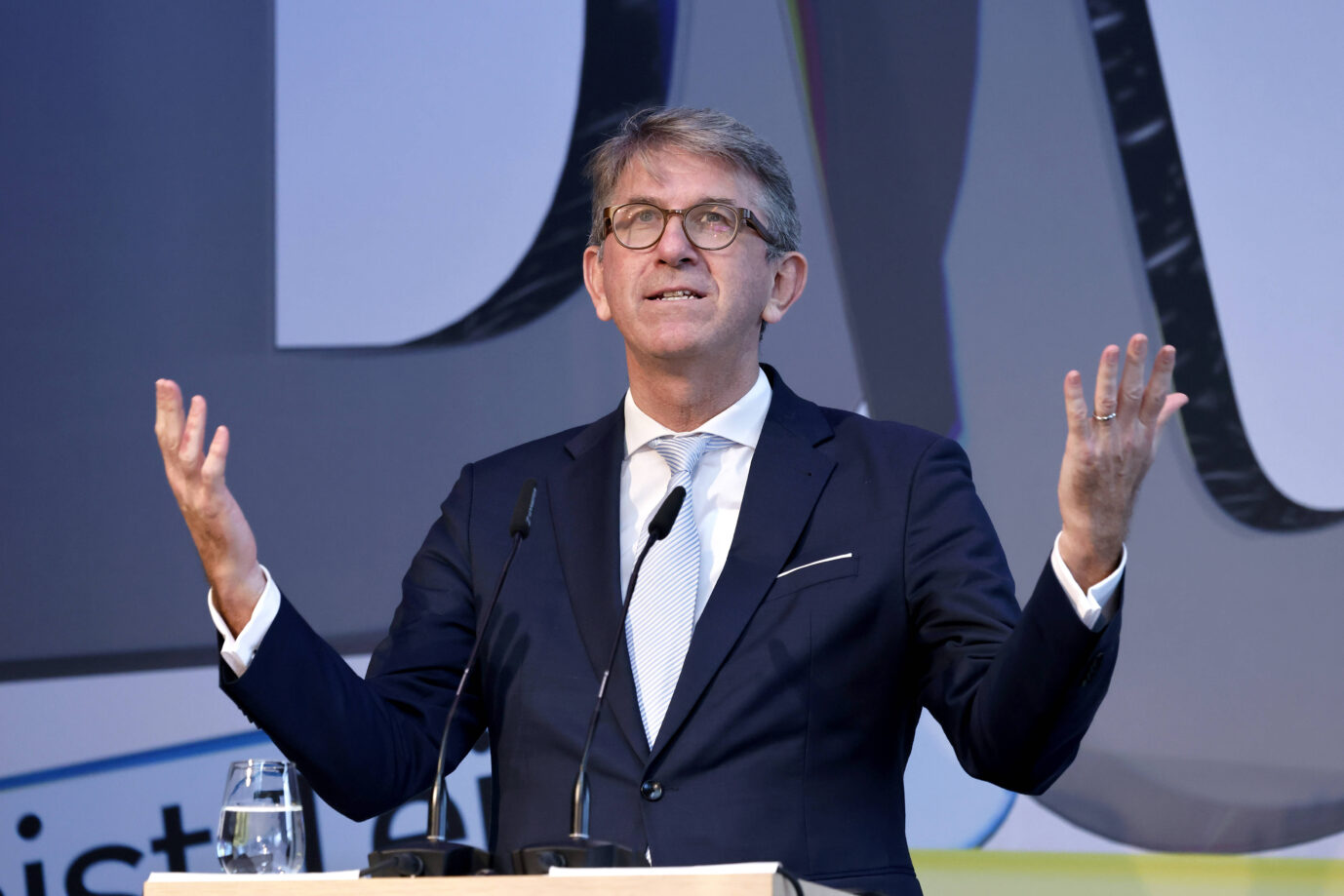 Kulturstaatsminister Wolfram Weimer steht da, in schwarzem Jackett und hält die Hände nach oben