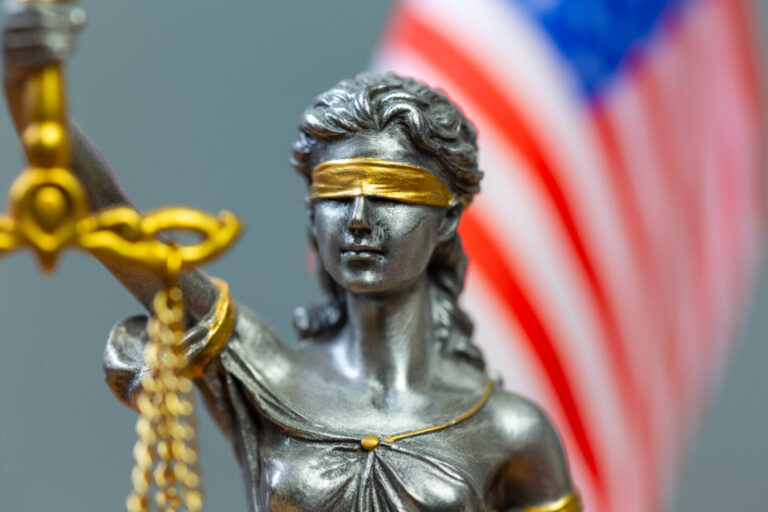 Justitia vor der Flagge der USA (Symbolbild): Der Oberste Gerichtshof der USA schiebt der kalifornischen Transideologie einen Riegel vor.