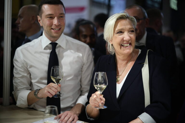 Der RN-Vorsitzende Jordan Bardella und die RN-Präsidentschaftskandidatin Marine Le Pen stehen nebeneinander und trinken Weißwein