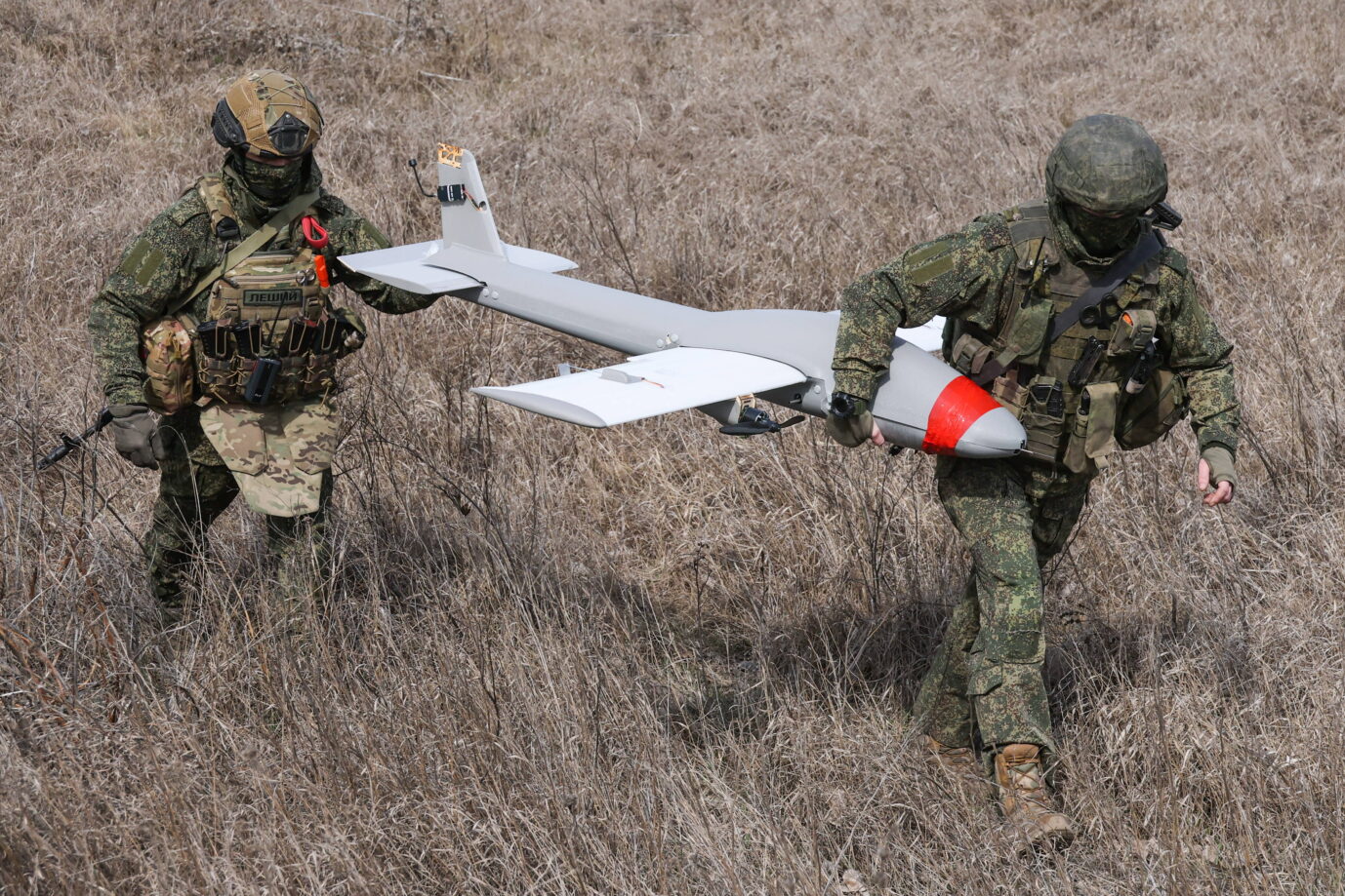 Zwei russische Soldaten tragen eine Drohne durch ein Feld