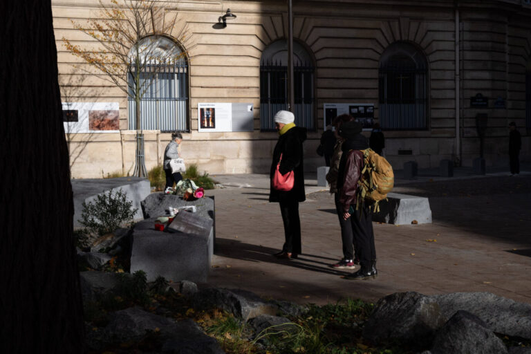 Eine Person legt Blumen am edenkgarten für die Opfer des 13. Novembers in Paris nieder