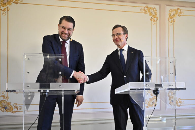 Zwei Politiker in Jackett und Krawatte schütteln sich die Hand – es sind Schwedendemokraten-Chef Jimmie Åkesson (links) und Ministerpräsident Ulf Kristersson bei einer gemeinsamen Pressekonferenz