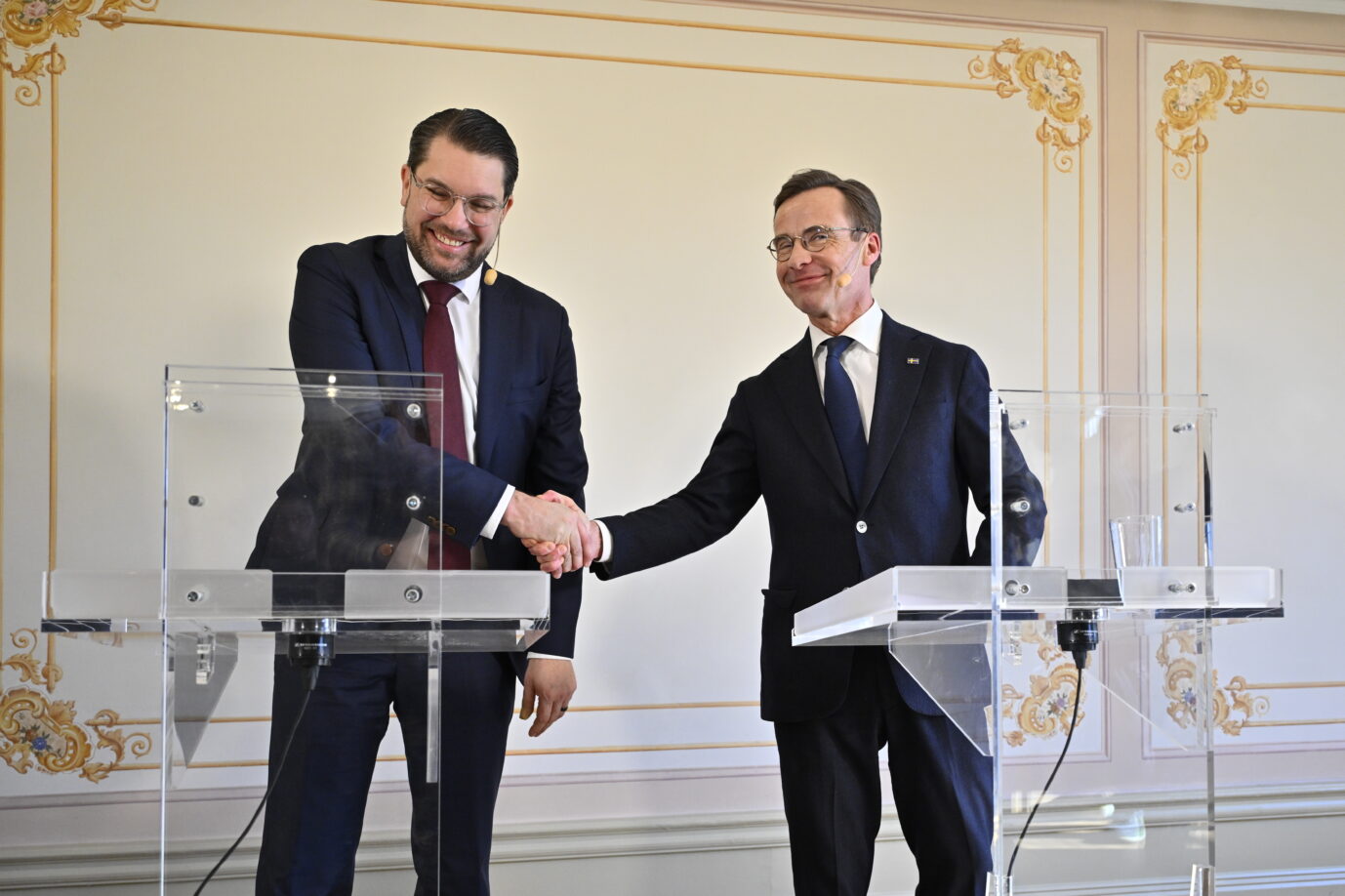 Zwei Politiker in Jackett und Krawatte schütteln sich die Hand – es sind Schwedendemokraten-Chef Jimmie Åkesson (links) und Ministerpräsident Ulf Kristersson bei einer gemeinsamen Pressekonferenz