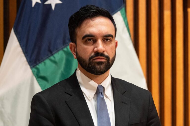 New Yorks Bürgermeister Zohran Mamdani (Demokraten) steht vor einer Flagge und guckt grimmig.