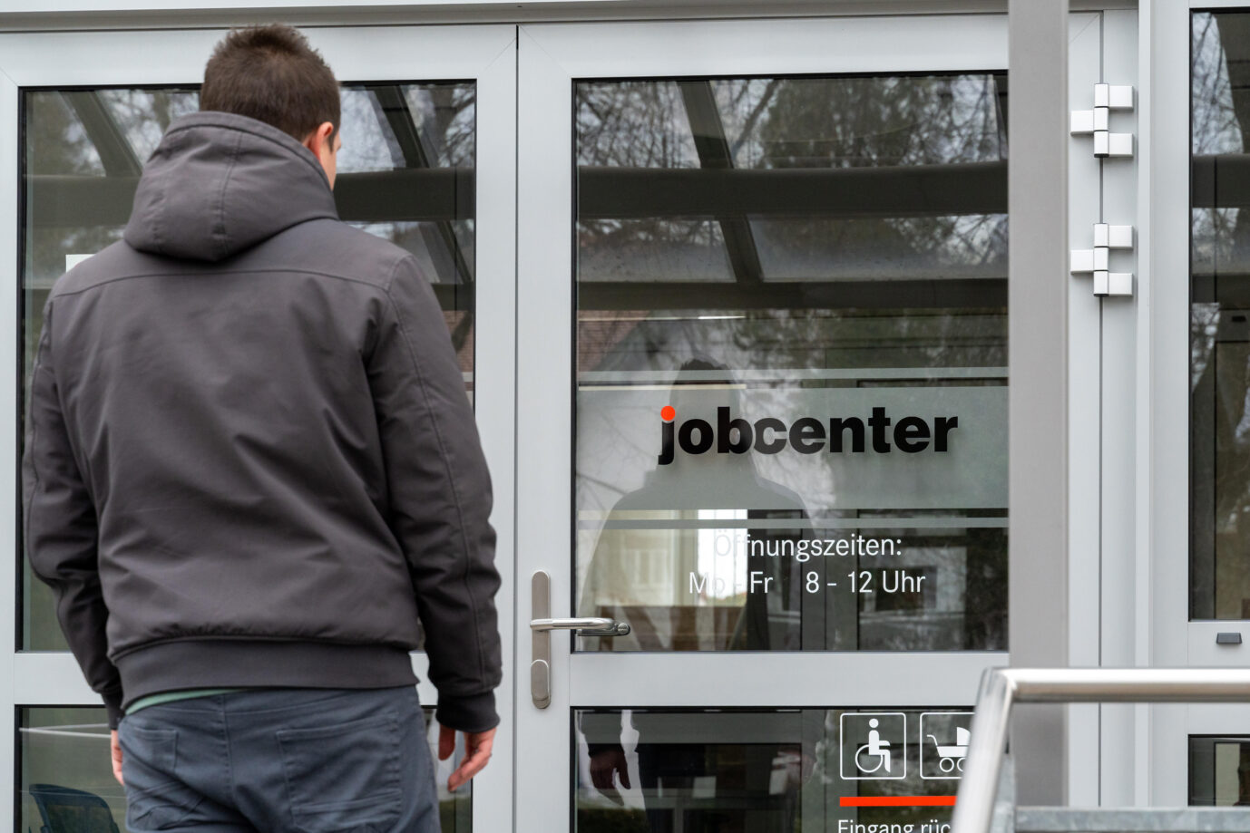 Ein junger Mann steht vor dem Eingang eines Jobcenters. Die Bundesagentur für Arbeit geht gegen Sozialleistungsbetrug vor.