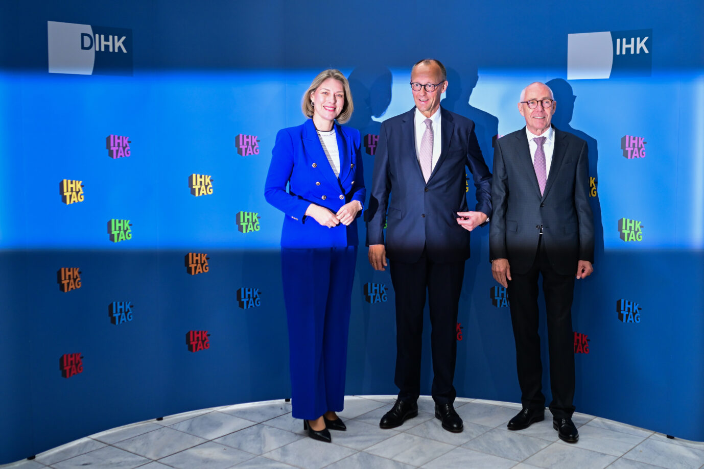 Helena Melnikov (l-r), Hauptgeschäftsführerin der Deutschen Industrie- und Handelskammer, Bundeskanzler Friedrich Merz (CDU) und Peter Adrian, Präsident der Deutschen Industrie- und Handelskammer, stehen während des IHK-Tags zum Thema "Wie wird Wirtschaft(en) in Deutschland einfacher?" im Haus der Deutschen Wirtschaft nebeneinander.