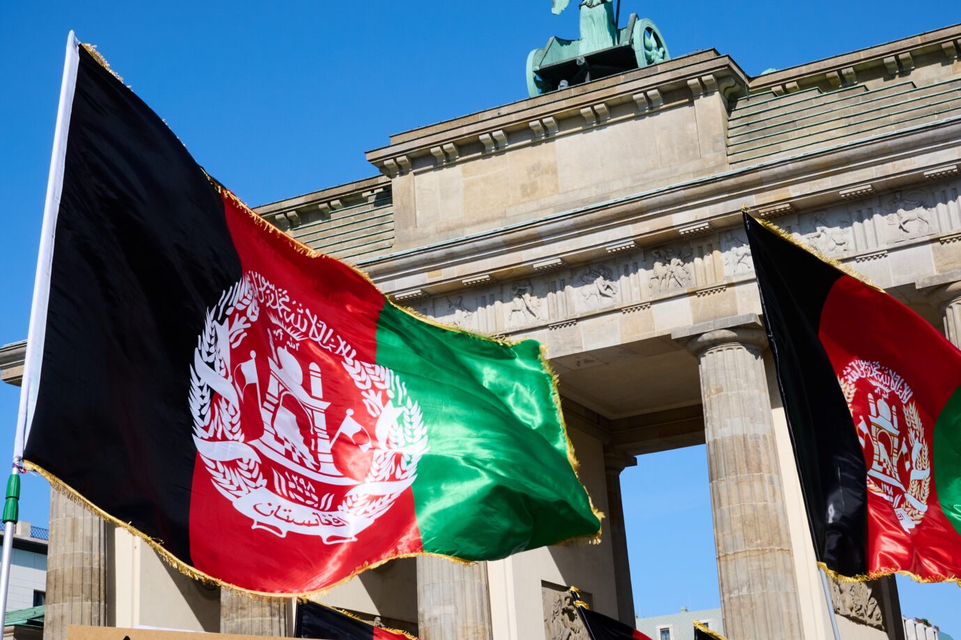 Menschen halten afghanische Flaggen vor dem Brandenburger Tor, bei einer Protestaktion gegen die radikalislamischen Taliban und ihren Vormarsch in Afghanistan. Afghanen gehen auch mit einer Förderung nicht zurück in ihr Heimatland.