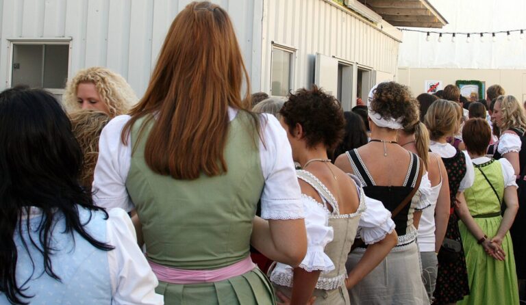 In Dirndl gewandete junge Damen stehen während des Oktoberfests vor dem Damenklo Schlange