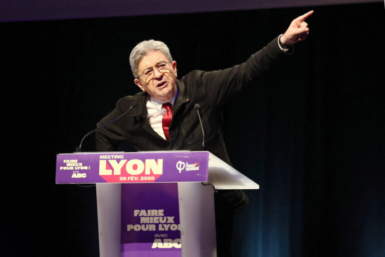 Der Präsidentschaftskandidat der LFI, Jean Luc Mélenchon, steht vor einem Rednerpult und zeigt mit seinem linken Arm nach oben, dabei steht ihm der Mund theatralisch offen
