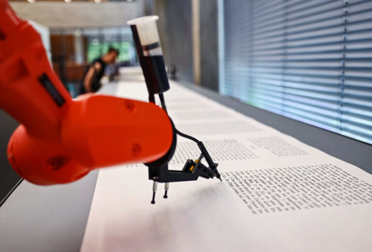 Ein Roboter schreibt die Bibel im Pforzheimer Reuchlinhaus nieder (Symbolbild): Immer häufiger greifen Buchautoren auf KI-Software wie ChatGPT zu. (Themenbild)