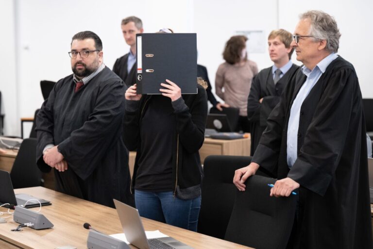 Lina E. von der Hammerbande hält sich einen Aktenordner vor das Gesicht