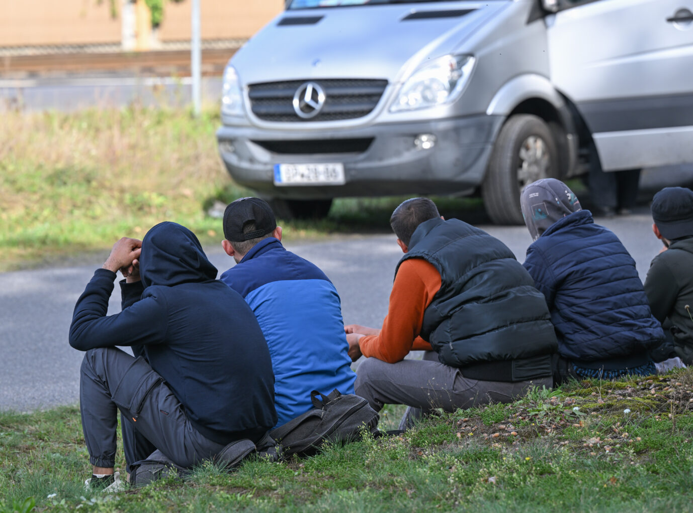 Unerlaubt eingereiste Asylbewerber sitzen nach einem Aufgriff durch Beamte der Bundespolizei am Straßenrand nahe der deutsch-polnischen Grenze in Forst (Lausitz). Bei mehreren Einsätzen im brandenburgischen Forst und Umgebung hatte die Bundespolizei am 11.10.2023 mindestens 64 unerlaubt eingereiste Migranten aufgegriffen. Sie wurden nach eigenen Angaben von Schleusern über die sogenannte Balkan-Route aus der Türkei über Griechenland, Bulgarien, Ungarn, die Slowakei und Polen nach Deutschland gebracht und kurz hinter der Grenze abgesetzt. Die Bundespolizei fahndet seit einigen Wochen verstärkt mit mobilen Kontrollen an der deutsch-polnischen Grenze nach Kriminellen, die Geflüchtete und Migranten unerlaubt nach Deutschland bringen.