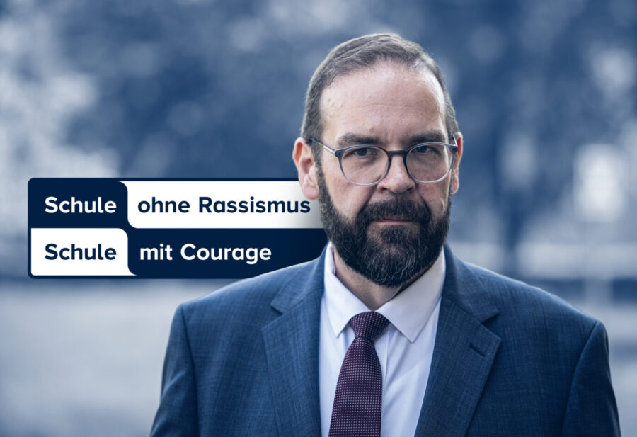 Brandenburgs Bildungsminister Gordon Hoffmann, daneben das Logo des Netzwerks „Schule ohne Rassismus – Schule mit Courage“