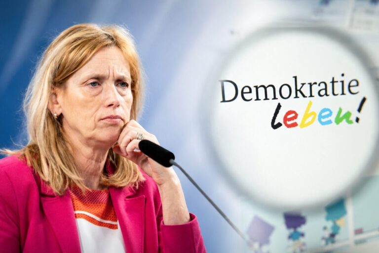 Bundesfamilienministerin Karin Prien neben einem Logo von „Demokratie leben!“